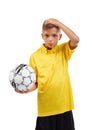 Serious, confused boy with a soccer ball holding his head isolated on a white background. School activities concept. Royalty Free Stock Photo