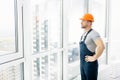 Serious construction engineer standing near window