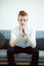 Serious contemplation. A red haired man sitting on a couch looking directly at the camera. Royalty Free Stock Photo