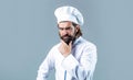 Serious cook in white uniform, chef hat. Portrait of a serious chef cook. Bearded chef, cooks or baker. Bearded male