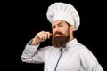 Serious cook in white uniform, chef hat. Portrait of a serious chef cook. Bearded chef, cooks or baker. Bearded male Royalty Free Stock Photo