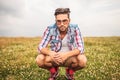 Serious crouched casual man in a field of grass Royalty Free Stock Photo
