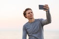 Serious Curly Sportsman making selfie on smartphone