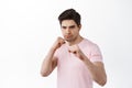 Serious determined man standing in boxing pose, fighting, ready to fight, defending from attack, standing in t-shirt