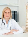 Serious doctor with model spine next to her looks