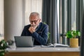 Serious elderly entrepreneur working on laptop while sitting at office desk Royalty Free Stock Photo