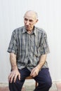 Serious elderly man sitting on chair