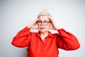 Serious elderly woman with glasses and a shirt holding her head and suffering from headache closing her eyes Royalty Free Stock Photo