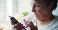 Serious elderly woman with smartphone - she searching web ang watching newsfeed.