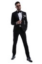 Serious elegant man in tuxedo holding hands in a fashion pose