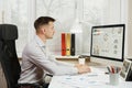 Serious and engrossed business man in shirt sitting at the desk, working at computer with modern monitor. Manager or worker.