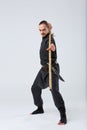 A man with long hair, in a special black kimono , practicing martial arts technique with a bamboo stick. Royalty Free Stock Photo