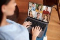 Serious european young woman communicating with headshot of friends on laptop screen