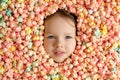 Serious face of a child surrounded by a large pile of multicolored popcorn