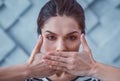 Resolute good-looking woman closing mouth with both hands