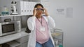 Serious-faced young pregnant woman scientist, wearing glasses, passionately immersed in her laboratory research