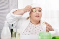 Serious fat woman making a cucumber mask