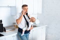 serious father holding infant daughter in baby carrier and talking on smartphone