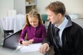 Serious father looks at his little daughter drawing picture