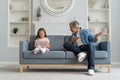 Serious father scolding little daughter in home interior.