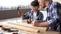 Serious father and son hammering nail in wooden plank, family leisure, support Royalty Free Stock Photo