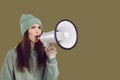 Serious female activist with megaphone in her hand makes loud announcement on brown background. Royalty Free Stock Photo