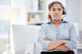 Serious female customer service worker with headphones at the office at a call center. Portrait of an IT tech support