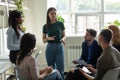 Serious female leader, mentor holding briefing for multiracial team interns. Royalty Free Stock Photo