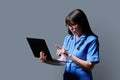 Female nurse using laptop, profile view on gray studio background Royalty Free Stock Photo