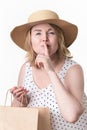 Female shopper raised finger to lips, makes secret sign, holds paper shopping bag in her other hand Royalty Free Stock Photo