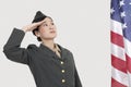 Serious female US military officer saluting American flag over gray background Royalty Free Stock Photo