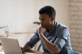 Serious focused African American businessman looking at laptop screen