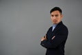 Serious and focused Asian businessman stands with arms crossed, isolated grey background Royalty Free Stock Photo