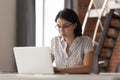 Serious focused asian female employee in glasses working with computer.