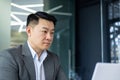 Serious and focused businessman working with laptop, man inside office building, asian boss typing on computer Royalty Free Stock Photo