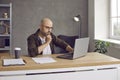 Serious focused businessman working on laptop sitting next to his morning takeaway coffee. Royalty Free Stock Photo