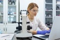 Serious and focused female researcher working with microscope inside laboratory, mature and experienced scientist Royalty Free Stock Photo