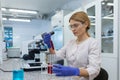 Serious and focused female researcher working with microscope inside laboratory, mature and experienced scientist