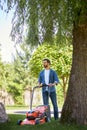 Serious, focused male handyman trimming fresh lawn with cordless mower in park. Royalty Free Stock Photo