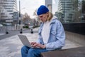 Serious focused millennial hipster guy freelancer sitting on city street replying to urgent email