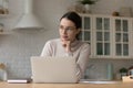Serious focused woman in glasses working on laptop at home