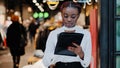 Serious focused young african american girl salesman female worker busy woman clothing store owner stands indoors using Royalty Free Stock Photo