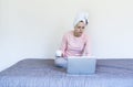 Serious and focused young woman with hair in a towel using a laptop computer, working remotely online, sitting at home Royalty Free Stock Photo