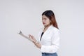 A serious and focused young woman holding a clipboard and a pen and looking at it. Isolated on a white background Royalty Free Stock Photo