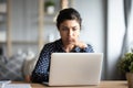 Serious frowning indian woman read email on laptop feels concerned