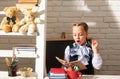 Serious funny school girl reading book in classroom at school. Kid studying at school. Schoolchild doing homework at Royalty Free Stock Photo