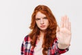 Serious ginger woman in shirt showing stop gesture at camera