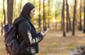 Serious girl with backpack using mobile phone in forest Royalty Free Stock Photo