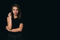 Serious girl on a black background. Beautiful girl in black on a dark background. The girl thinks about her problem Royalty Free Stock Photo