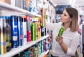 Serious girl looking hair care products at showroom Royalty Free Stock Photo